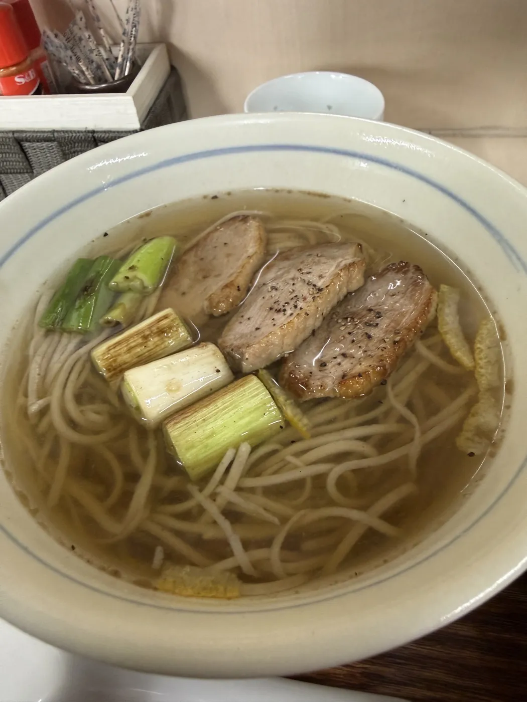 A close-up of kamo nanban soba at Kiyoka in Minamioguni: three slices of seared duck with black pepper, charred white leeks and green onion tops on thin soba in clear broth